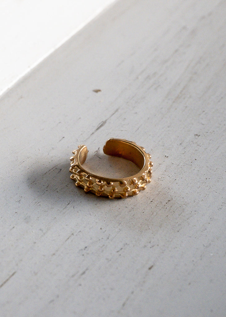 Nesrin. Gold earcuff, with tiny, embossed beads on its surface.