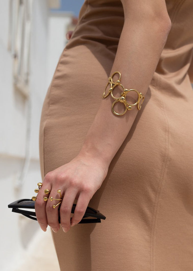 close up woman's arm with pendulum bracelet, gold