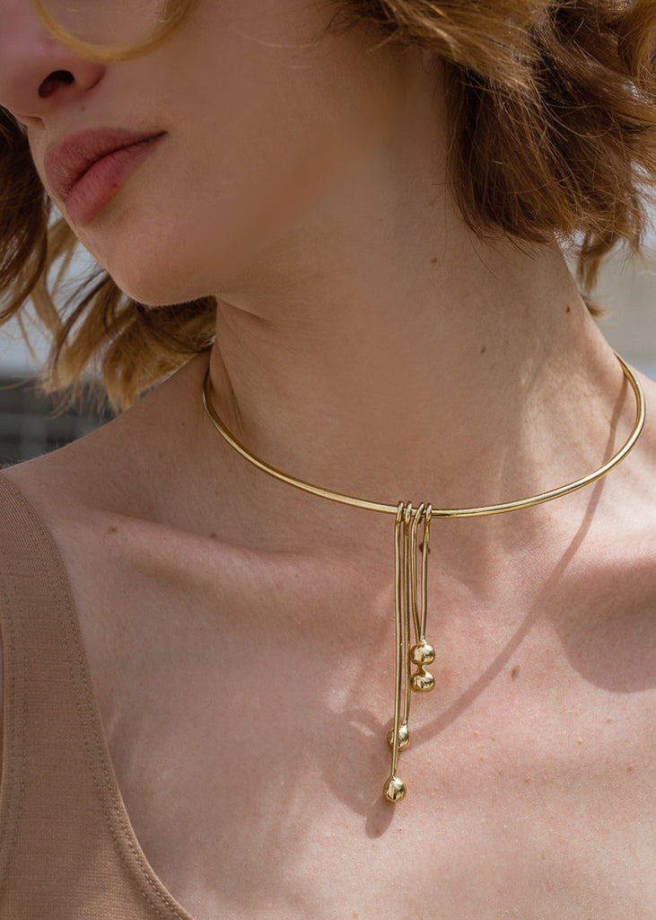 woman wearing, a pendulum necklace gold
