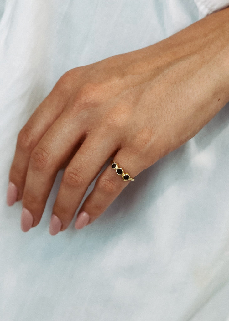 Χειροποίητο δαχτυλίδι Eday χρυσό με τρεις πέτρες Swarovski μαύρες, φορεμένο στο χέρι μοντέλου.