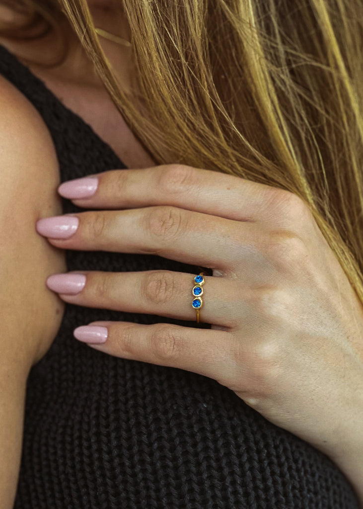 Χειροποίητο δαχτυλίδι Eday χρυσό με τρεις πέτρες Swarovski μπλε, φορεμένο στο χέρι μοντέλου.