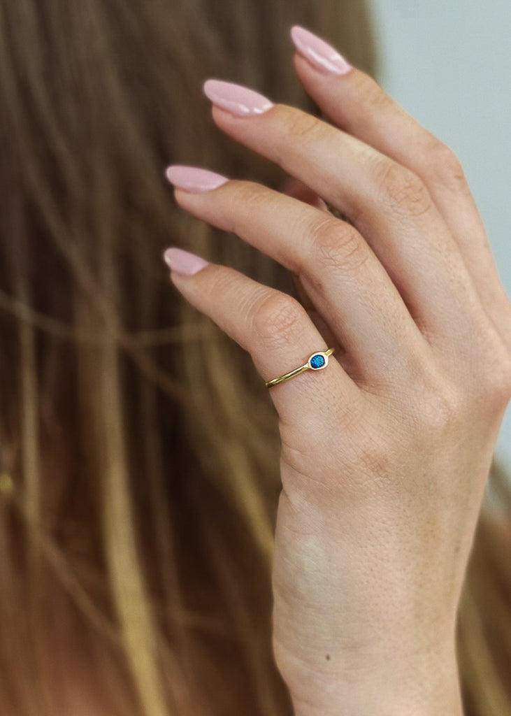 Χειροποίητο δαχτυλίδι Eday χρυσό με μία πέτρα swarovksi μπλε, φορεμένο στο χέρι μοντέλου.