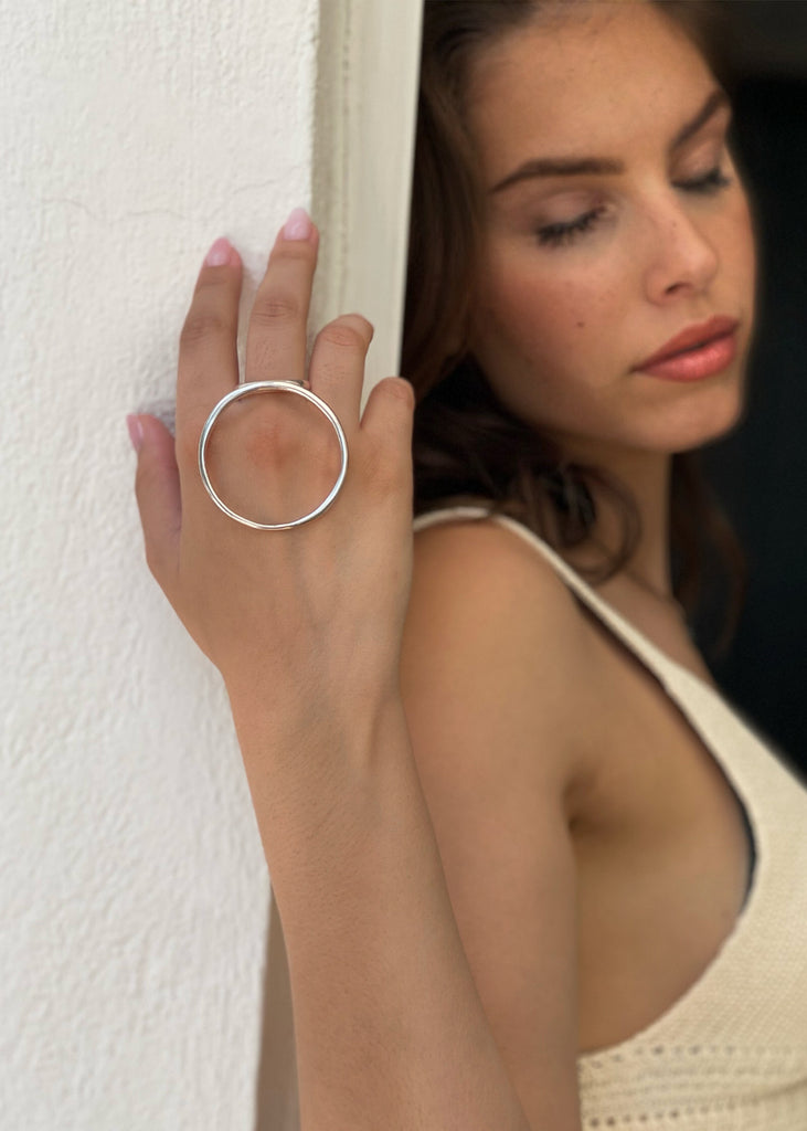 woman close up, wearing a Handmade, silver ring with a large circular rod mounted on a simple shank
