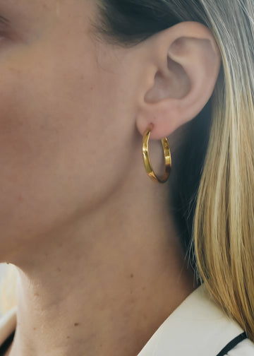 Blond female's left profile. On her ear she is wearing a gold, flat loop earring by 3rd Floor Handmade Jewellery