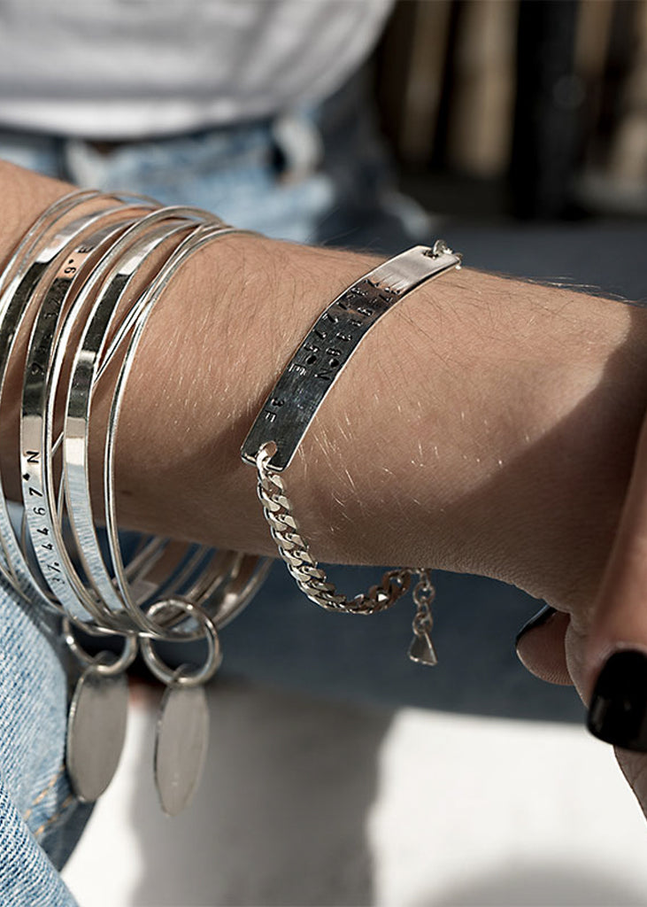 Close up of girl's hand wearing silver handmade coordinates line bracelets by 3rd Floor Handmade Jewellery