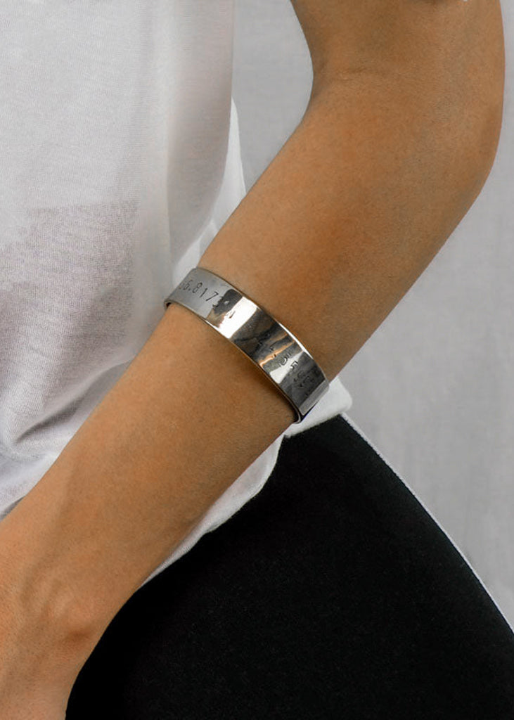 girl's forearm with a silver coordinates stamped bracelet by 3rd Floor handmade jewellery
