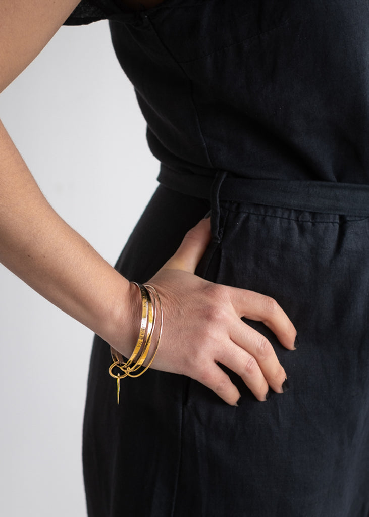 woman in black with  right hand on hip wearing a gold multi bangle bracelet, taxidi, by 3rd Floor Coordinates Line