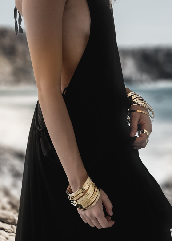 model in black dress wearing many bracelets roadtrip gold
