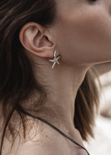 girl on the beach wearing Small Starfish, handmade earrings silver