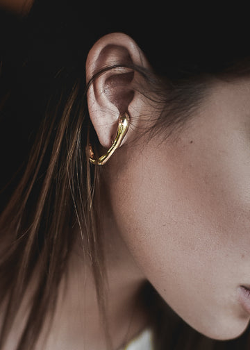 close up to a girl's ear wearing the handmade earrings Stem in gold color