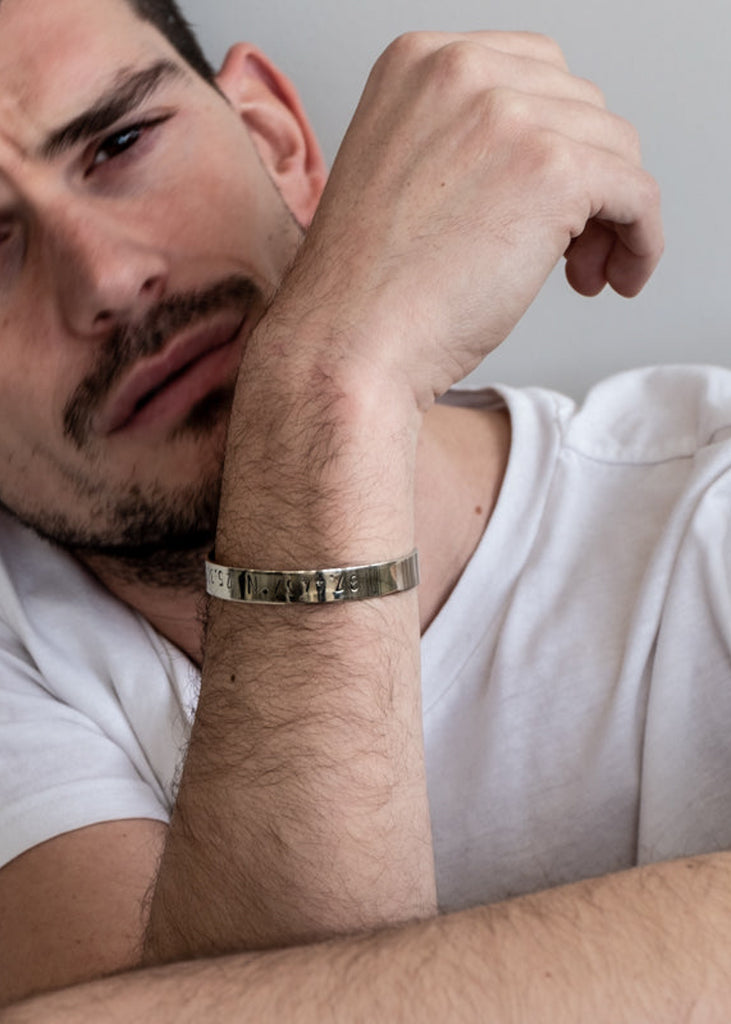 man wearing handmade silver plated adjustable bangle stamped with longitude and latitude coordinates