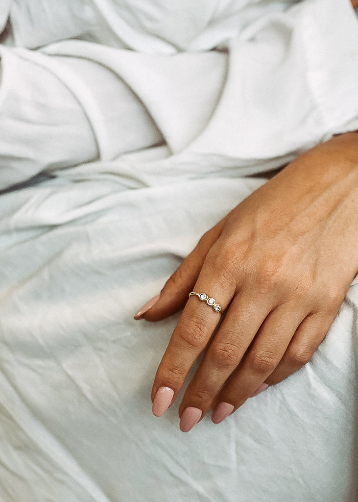 Χειροποίητο δαχτυλίδι Eday χρυσό με τρεις πέτρες Swarovski διάφανες, φορεμένο στο χέρι μοντέλου.