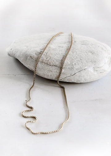 Silver, box chain necklace, half placed on a white stone